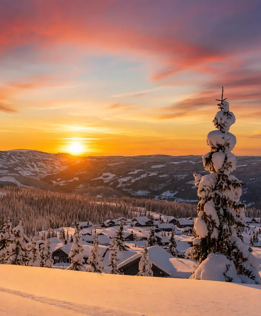 Solnedgång över snöklädda stugor